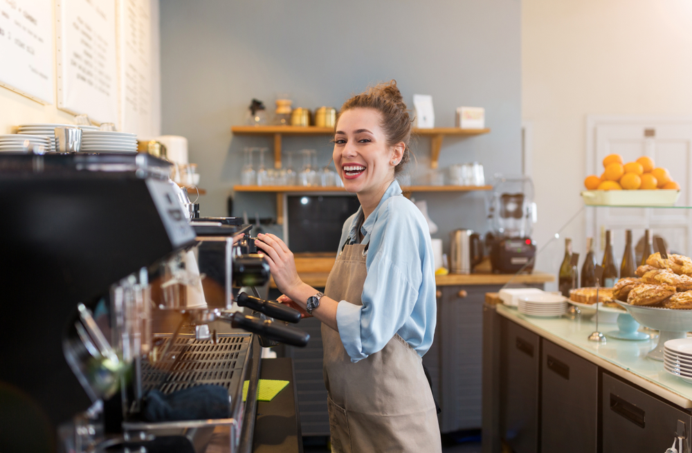 image shows barista smiling and preparing coffee for customer
